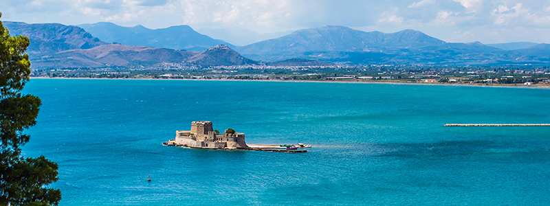 Öppet turkost hav med bergen i bakgrunden i den grekiska staden Nafplio.